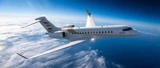 Private jet flying high above a layer of fluffy white clouds and blue water